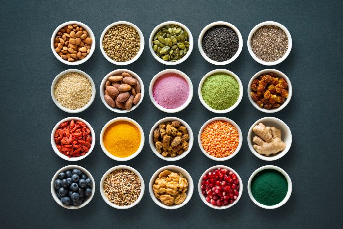 Aerial view of 24 small ramekins lined up and filled with various spices beans and other foods