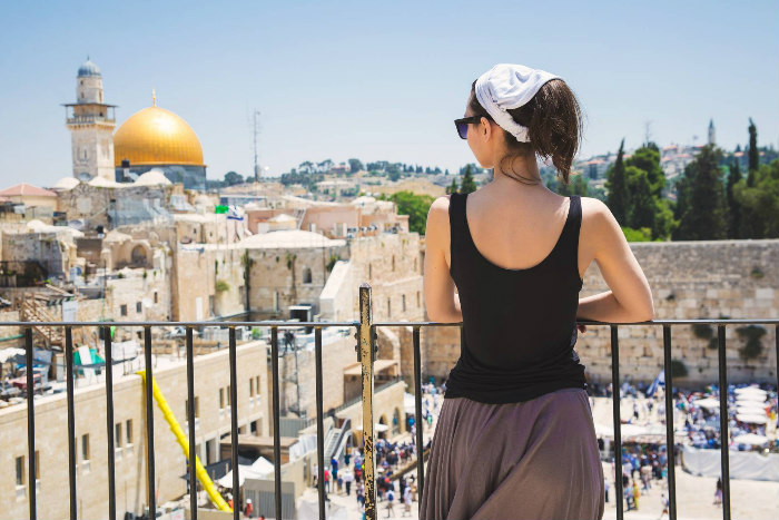 Woman standing on a balcony overlooking the Western Wall and Jerusalem