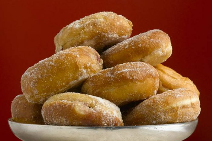 Pile of donuts on a silver platter against a red background