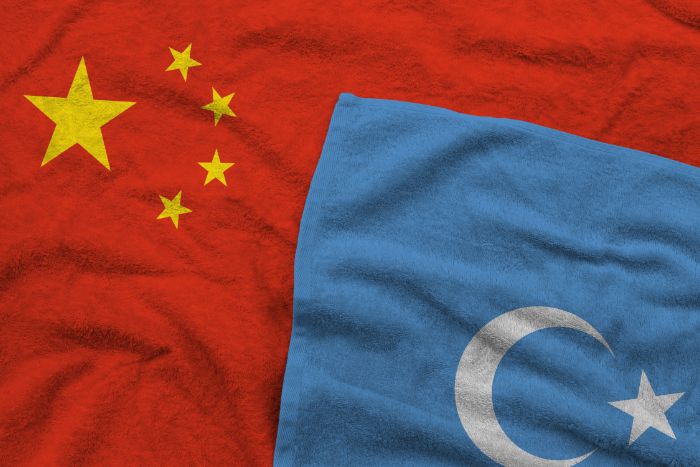 Red Chinese flag and blue Uyghur flag lying atop one another