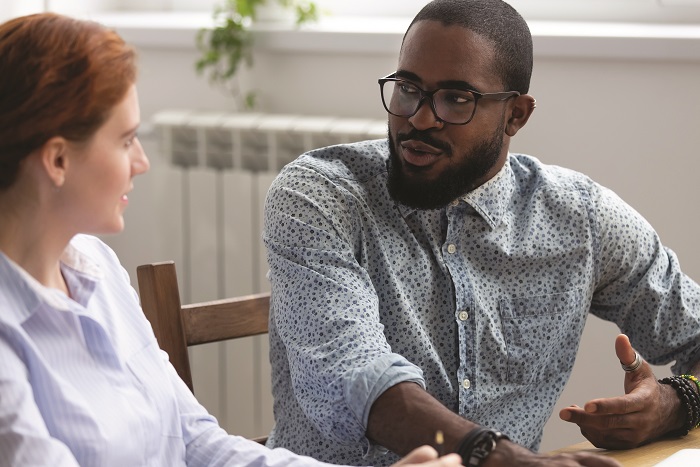 an image of two people of different races sitting and talking