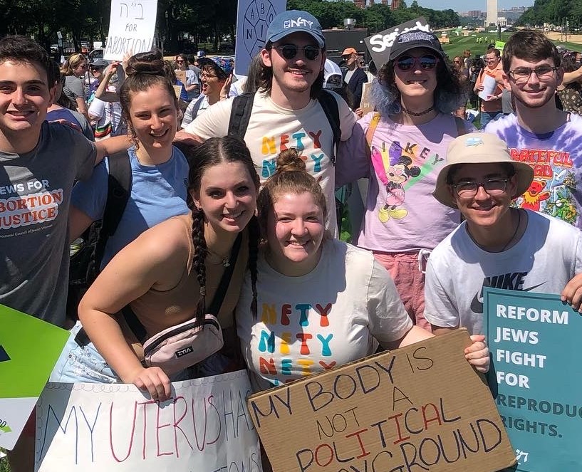 A group of young people stand holding pro-choice signs at the Jewish Rally for Abortion Justice