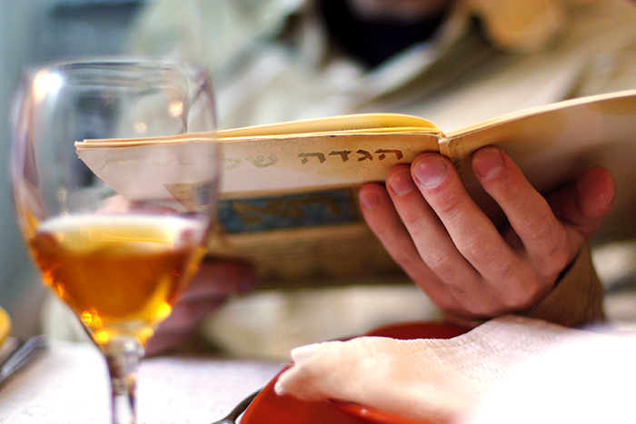 an image of a passover seder with a glass of wine and Haggadah