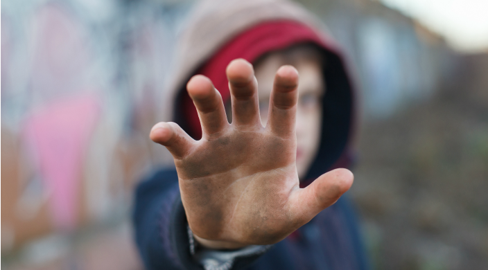 Child covering his face by holding a dirty hand up to the camera 