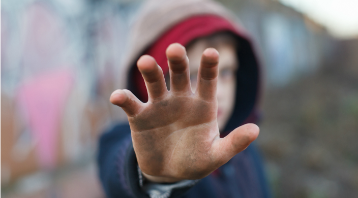 Child covering his face by holding a dirty hand up to the camera