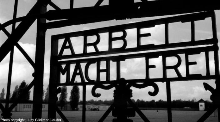 Judy Glickman Lauders black and white photo of Auschwitz gate entrance reading ARBEIT MACHT FREI