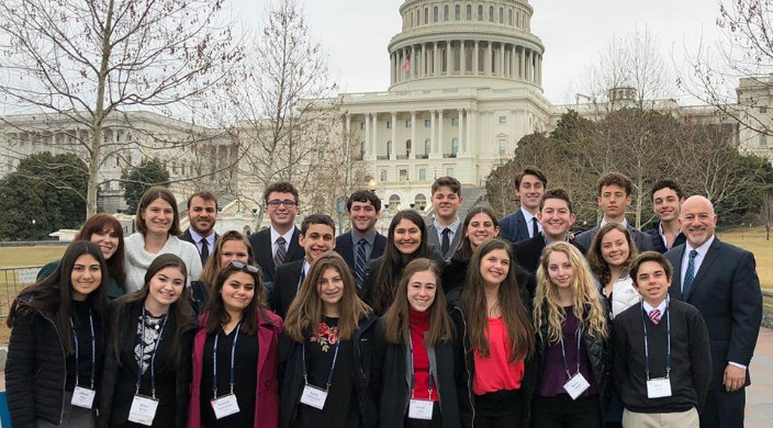 Large group of teenagers posing with Rabbi Paul Kipnes in front of the US Capitol Building 