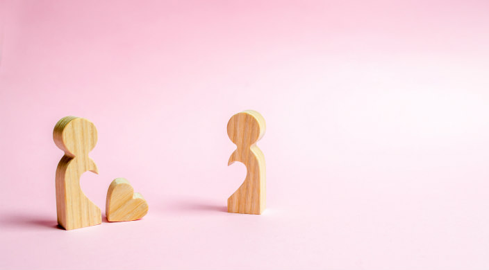 Two person shaped puzzle pieces against a pink background