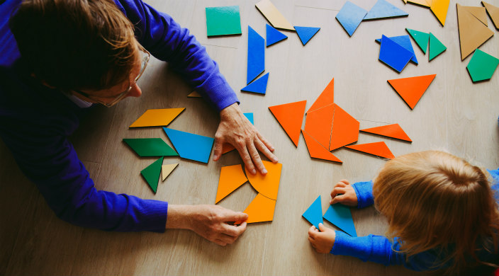 Overhead shot of adult and child on the floor playing with geometric shapes 
