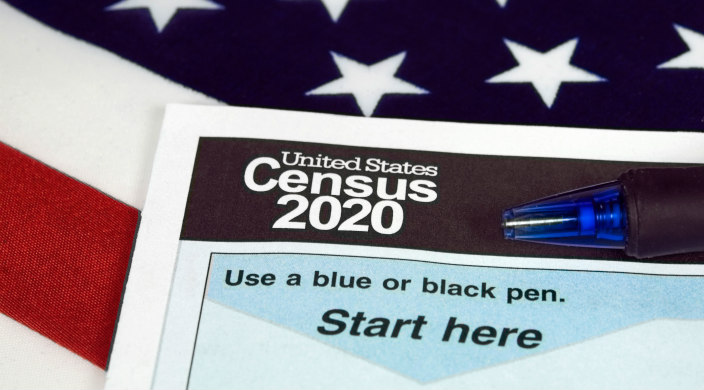 Corner of census form and a pen atop stars and stripes of the American flag