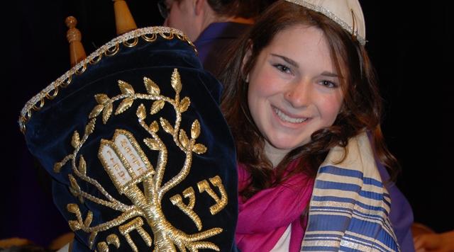 a girl holding up a Torah during her Bat Mitzvah