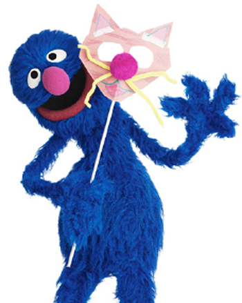 Grover, a character from Shalom Sesame, holding a mask for Purim, one kind of costume worn on the Jewish holiday