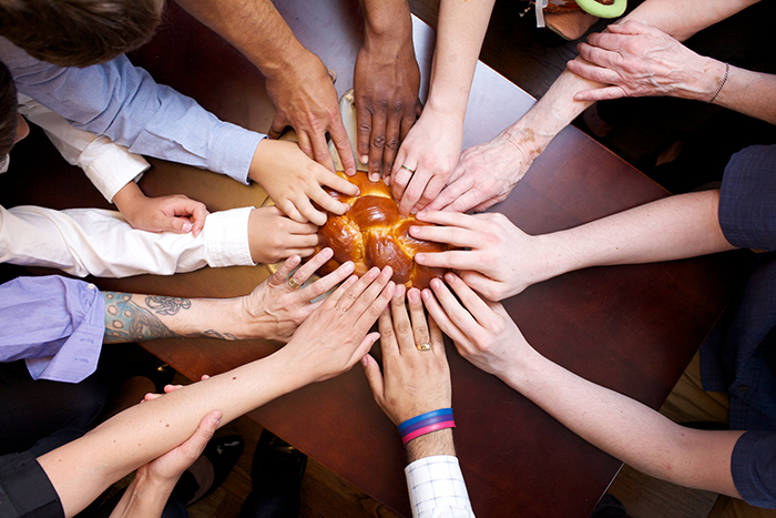 group of hands reaching for a challah