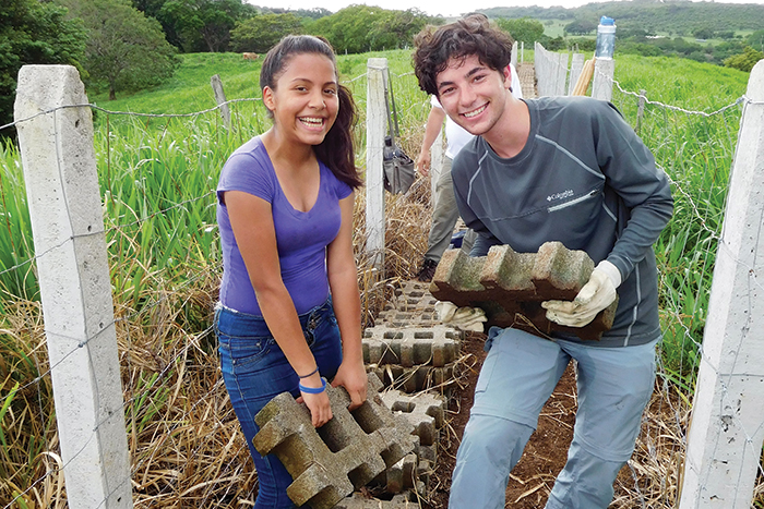 Two Mitzvah Corps participants working in a field and smiling