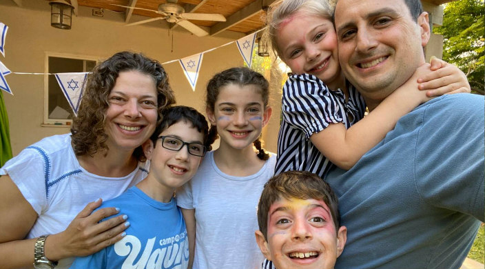 Smiling family taking a selfie together with Israeli flag pennants in the background