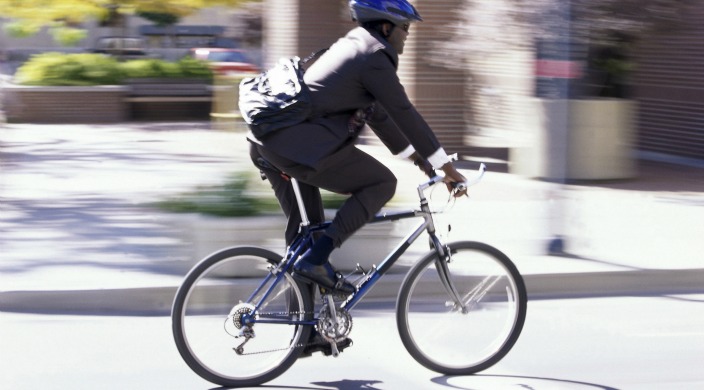 Man in business suit with messenger bag and helmet riding a bicycle