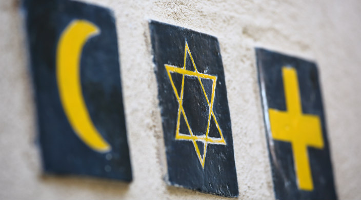 Three seperate tiles on an adobe wall representing three religions: Islam, Judaism, Christianity
