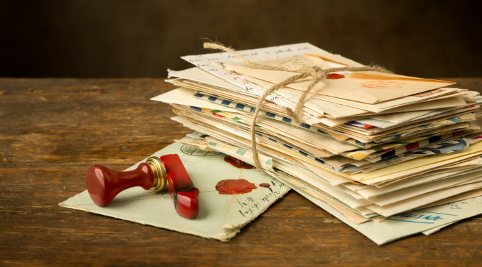 Stack of old letters tied with string; sealing wax and seal atop one loose letter