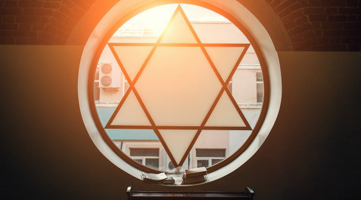 Circular stained glass window featuring a Star of David with open books sitting in the window sill