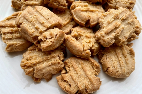 White plate full of small techina cookies with fork prints on top