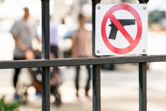 Sign on a fence with a red line through a gun