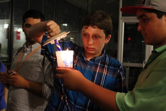 boys at camp distinguishing the havdalah candle into the wine