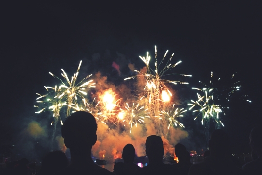 people silhouetted against multicolored fireworks