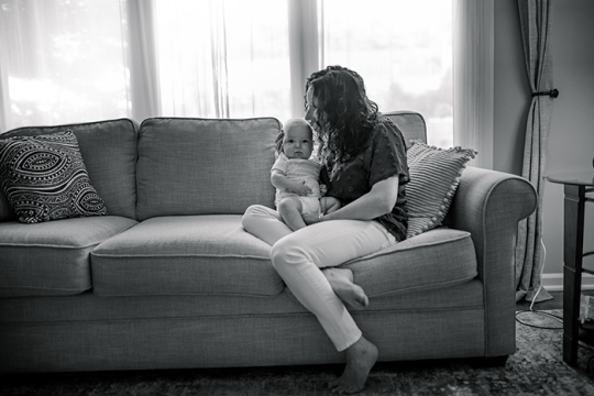 a black and white image of a woman holding her baby on her lap