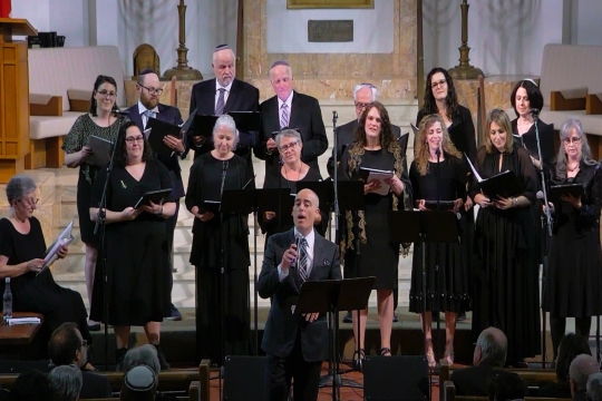 A choir, all dressed in black, sings facing the camera