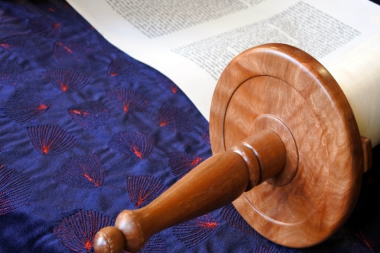 Closeup of a Torah unscrolled on blue fabric 