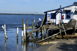 Fishing shack on the water with damage from a hurricane