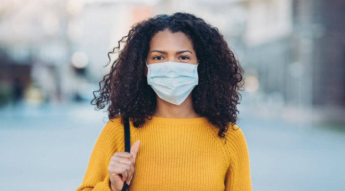 Young Black woman wearing a face mask outdoors 